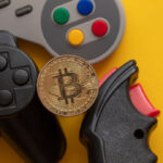 Controles de videogames e uma moeda dourada de Bitcoin (BTC)