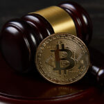 Martelo e bitcoin em uma mesa de madeira