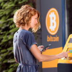 Mulher operando um caixa eletrônico de Bitcoin