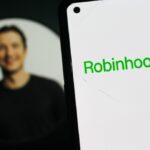 Logotipo da Robinhood em um smartphone, com a foto de perfil do CEO Vladimir Tenev ao fundo