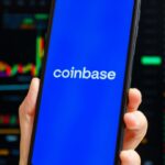 celular com logo da coinbase com graficos no fundo